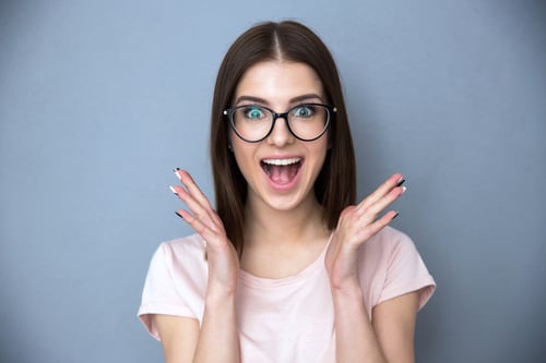Surprised young woman in glasses over gray background-3